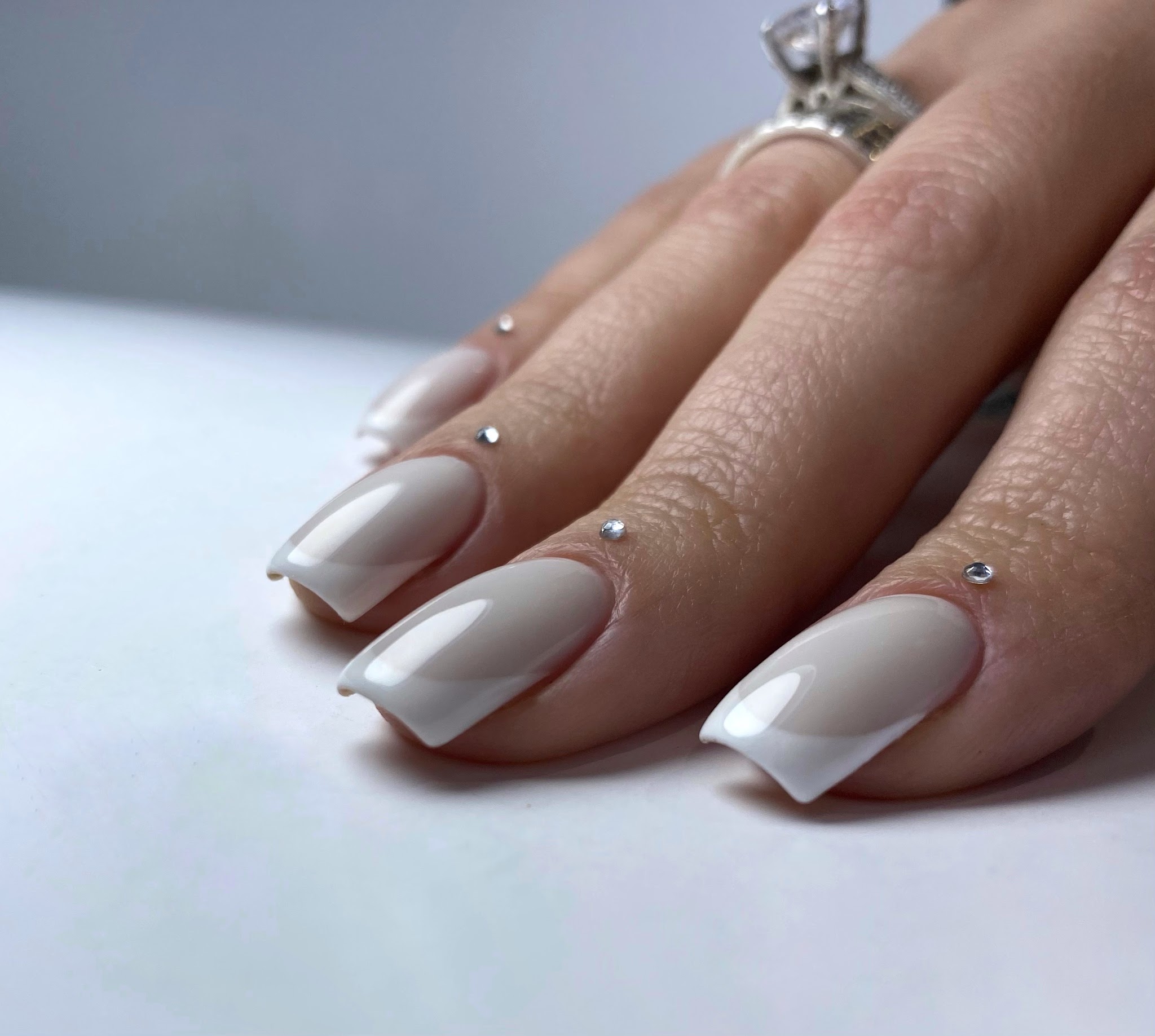 Witte vierkante nagels met French en kleine kristallen, BIAB op de natuurlijke nagel